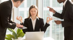 工作压力——平静的女人在办公室被愤怒的同事包围